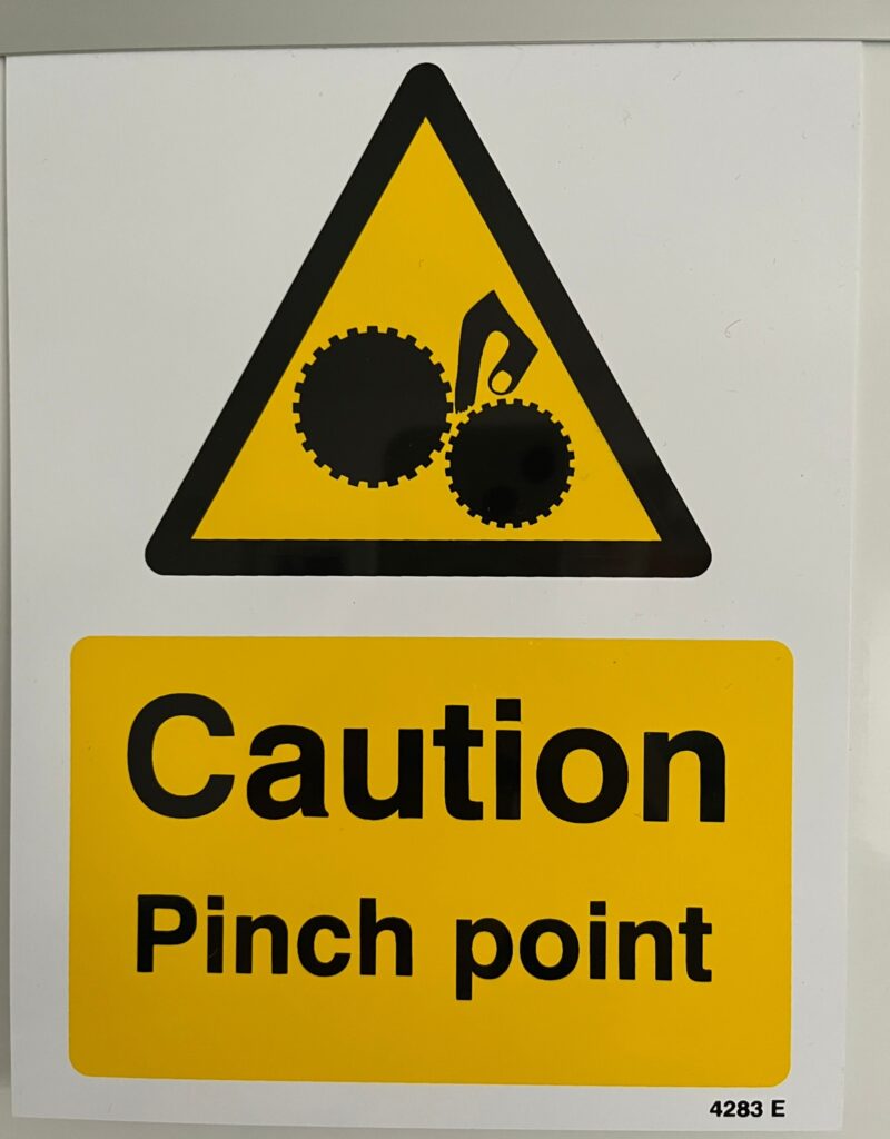 Foto eines Warnschildes, Aufschrift: Caution Pinch Point